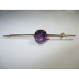 A large unmarked but tested as gold bar brooch with large purple stone