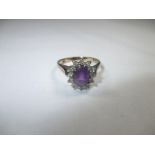 A 9ct gold diamond ring with central amethyst, approx ring size N