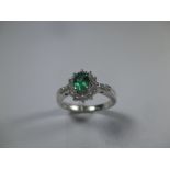 A platinum diamond and emerald ring with baguette diamonds to shoulders, approx finger size L 1/2