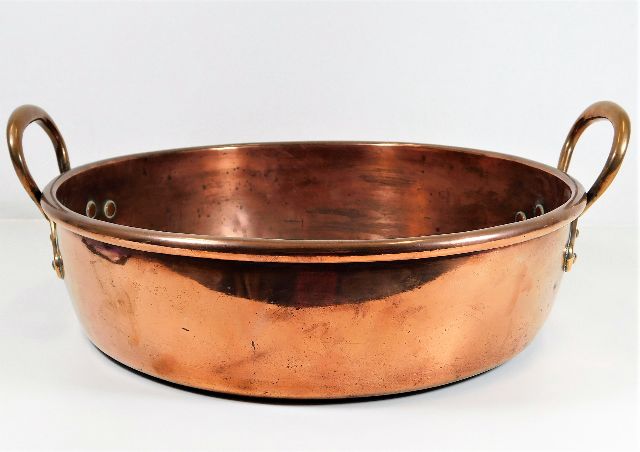 A large copper pan with brass handles 17in wide
