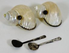 A pair of caviar serving shells with spoons