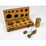 A cased set of gold weights, a brass lens case & a