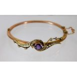 An antique yellow metal amethyst & pearl bangle wi