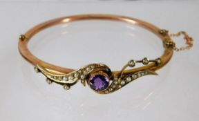 An antique yellow metal amethyst & pearl bangle wi
