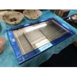 An art deco style wall mirror with blue glass bord