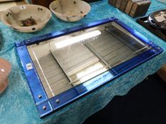 An art deco style wall mirror with blue glass bord