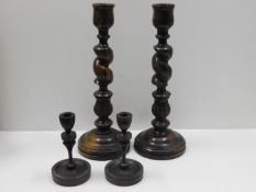 A pair of large wooden candlesticks twinned with one other pair