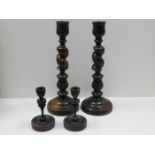 A pair of large wooden candlesticks twinned with one other pair