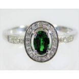 A 9ct white gold ring set with diamond & green gar