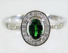 A 9ct white gold ring set with diamond & green gar