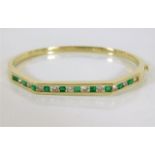 A 14ct gold bangle set with diamond & emerald 19g