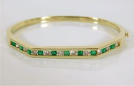 A 14ct gold bangle set with diamond & emerald 19g