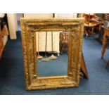 A large gilt coloured decorative mirror 115cm x 90