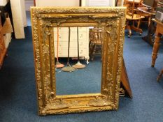 A large gilt coloured decorative mirror 115cm x 90