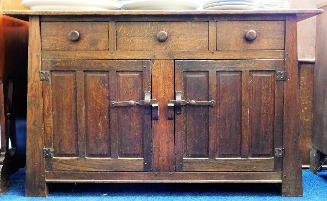 An arts & crafts style oak sideboard with three dr