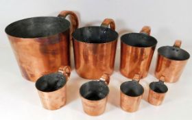 Set of eight graduated antique copper rum measures, largest one gallon