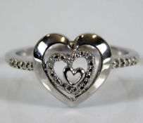 A 9ct white gold ring with heart shaped decor set