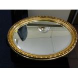 Oval gilt framed mirror twinned with one other mir