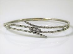 An 18ct white gold bangle set with approx. 1ct of