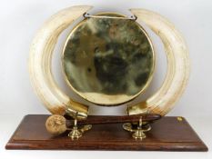 An antique brass dinner gong mounted on hippo tusk