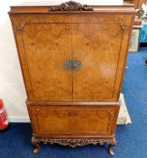 A mid 20thC. drinks cabinet with carved frieze between cabriole legs & carved finial 64inH x 36.25in