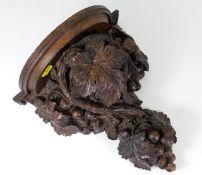 An antique carved oak wall sconce depicting grapes