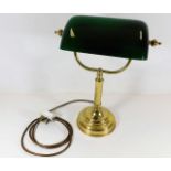 A brass desk lamp with lined glass shade