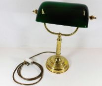 A brass desk lamp with lined glass shade