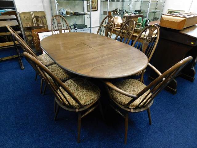 An Ercol mid-oak extending dining table with eight swan back chairs 67in L x 43in W x 29in H