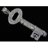 An 18ct white gold pendant as a key, encrusted wit