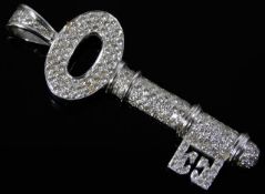 An 18ct white gold pendant as a key, encrusted wit