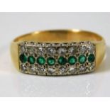 A yellow metal ring, tests as 18ct gold with approx. 0.16ct diamond & emerald ring 5g