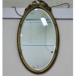 A gilt framed oval mirror with decor to top 25in h