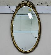 A gilt framed oval mirror with decor to top 25in h