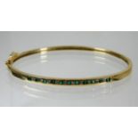 A 10ct gold diamond & emerald bangle 8.3g