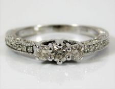 A 9ct white gold ring set with 0.25ct diamond with additional pave set diamonds on shoulders & shank