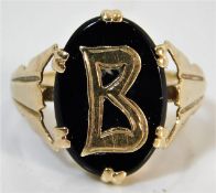 A yellow metal ring set with onyx with letter B si
