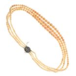 Graduated three string pearl choker having a diamond mounted oval clasp with central woven hair