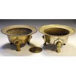 Pair of Oriental brass circular vessels, each standing on three pad supports, together with a