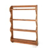 Stained pine open wall rack of four shelves between shaped supports, 65cm wide x 86cm high