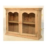 Vintage stripped table-top cabinet with a pair of double-arched glazed doors enclosing single shelf,