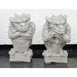 Pair of reconstituted figures of orcs or gargoyles, each holding a shield on square base, 38cm
