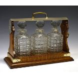 Edwardian oak three bottle tantalus of typical design with military dedication 'Presented to Col.