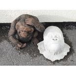 Reconstituted garden ornament formed as a gorilla mask, together with another modelled as a standing
