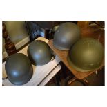 Four military-style green plastic helmets, each with internal tan leather fittings and stamps HBA