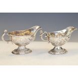 Matched pair of George II/George III silver pedestal cream boats, each having a figural scroll