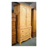 Stripped pine cabinet on chest having a moulded top over arch-panelled doors enclosing two