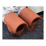 Two terracotta chimney cowls, each with curved hood over cylindrical socket, the larger 33cm long