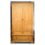 Modern pine wardrobe of two panelled doors enclosing hanging space over base drawer, 112cm wide x
