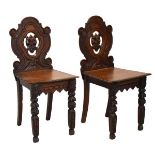 Pair of Victorian carved oak hall chairs, the shaped backs with central mask head decoration, hard